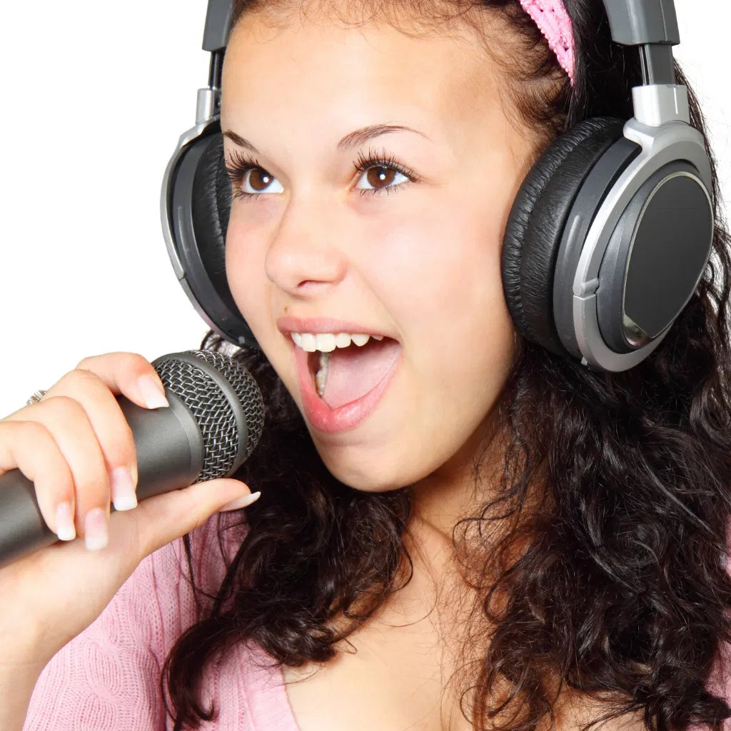 A young student singing into a professional microphone while wearing over-ear headphones, capturing the energy of a vocal les